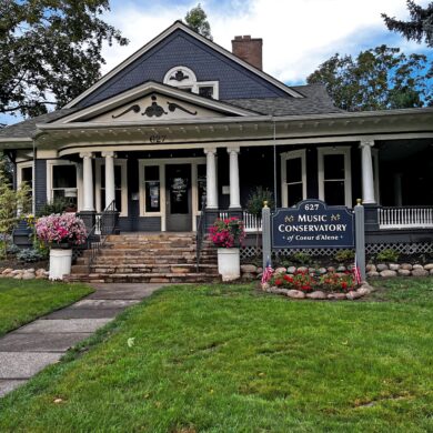 A 100 year old house painted blue on a lawn in the day time.