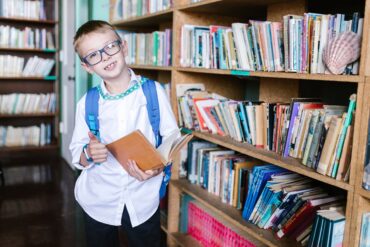 boy in white long sleeve shirt wearing eyeglasses holding a book