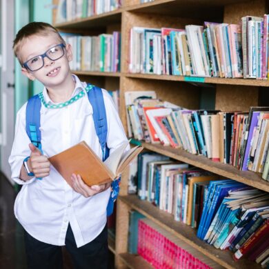 boy in white long sleeve shirt wearing eyeglasses holding a book