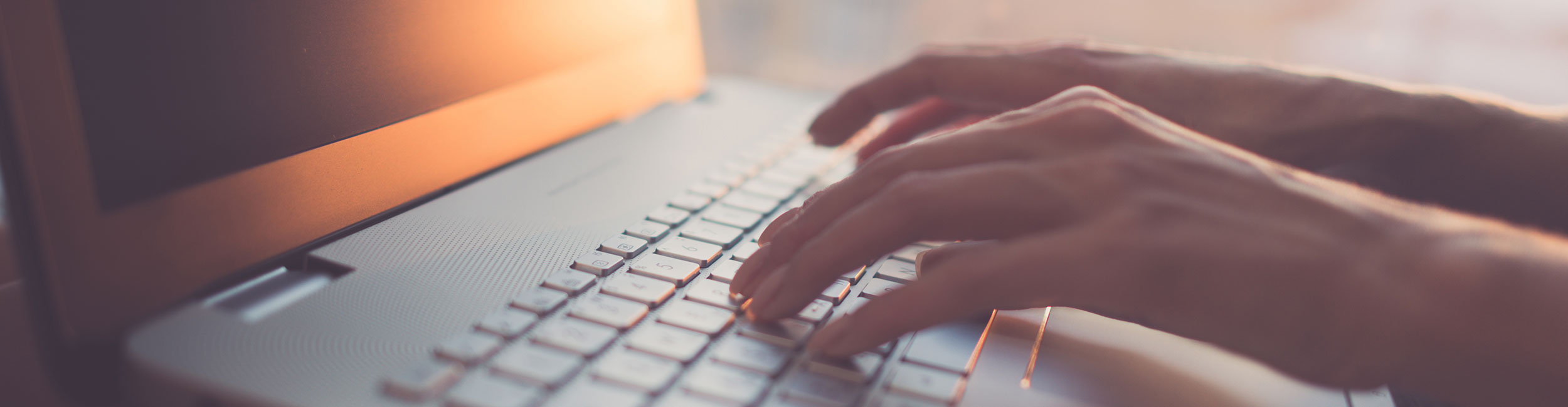 Hands typing on a laptop keyboard